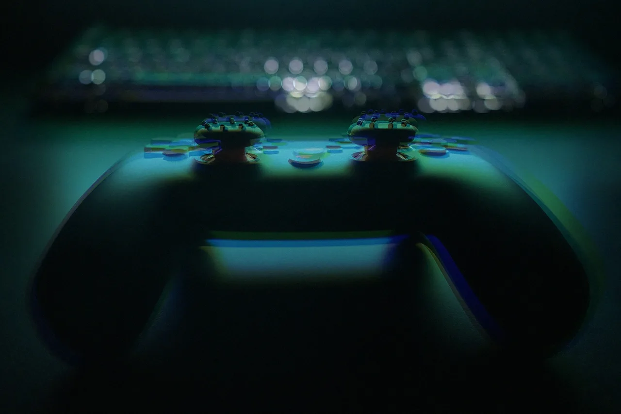 A game controller and a keyboard on a desk in low light